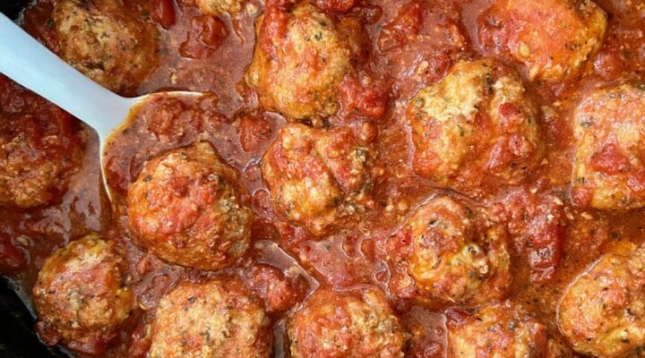 Turkey meatballs in a slow cooker with a white spoon