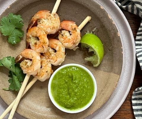 two shrimp skewers with green avocado sauce